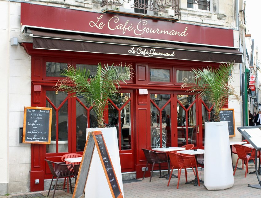 ogródek przy restauracji ze stolikami i krzesłami oraz donicą z egzotyczną palmą