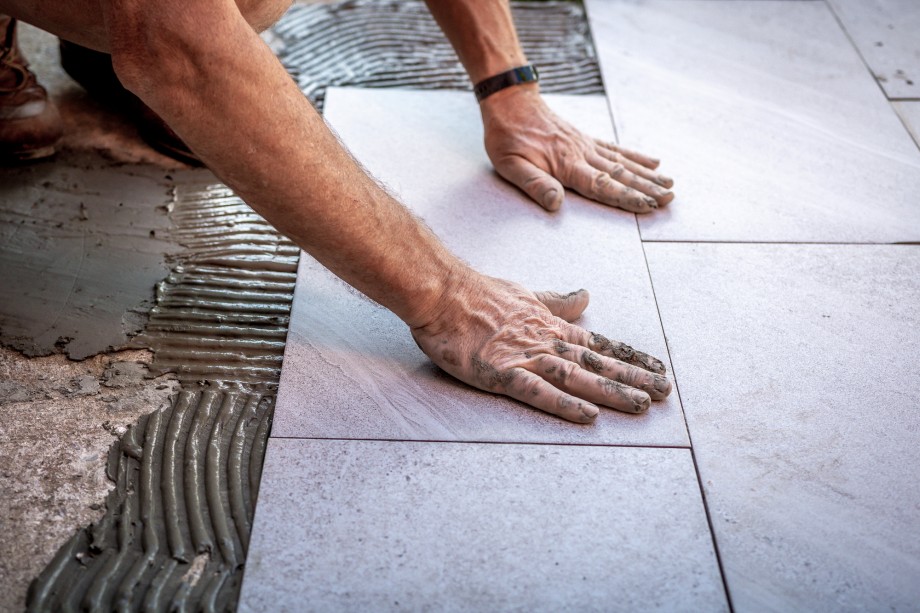 fachowiec układa ceramiczne płytki na tarasie