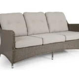 Trzyosobowa sofa Hornbrook z technorattanu z jasnoszarymi poduszkami.