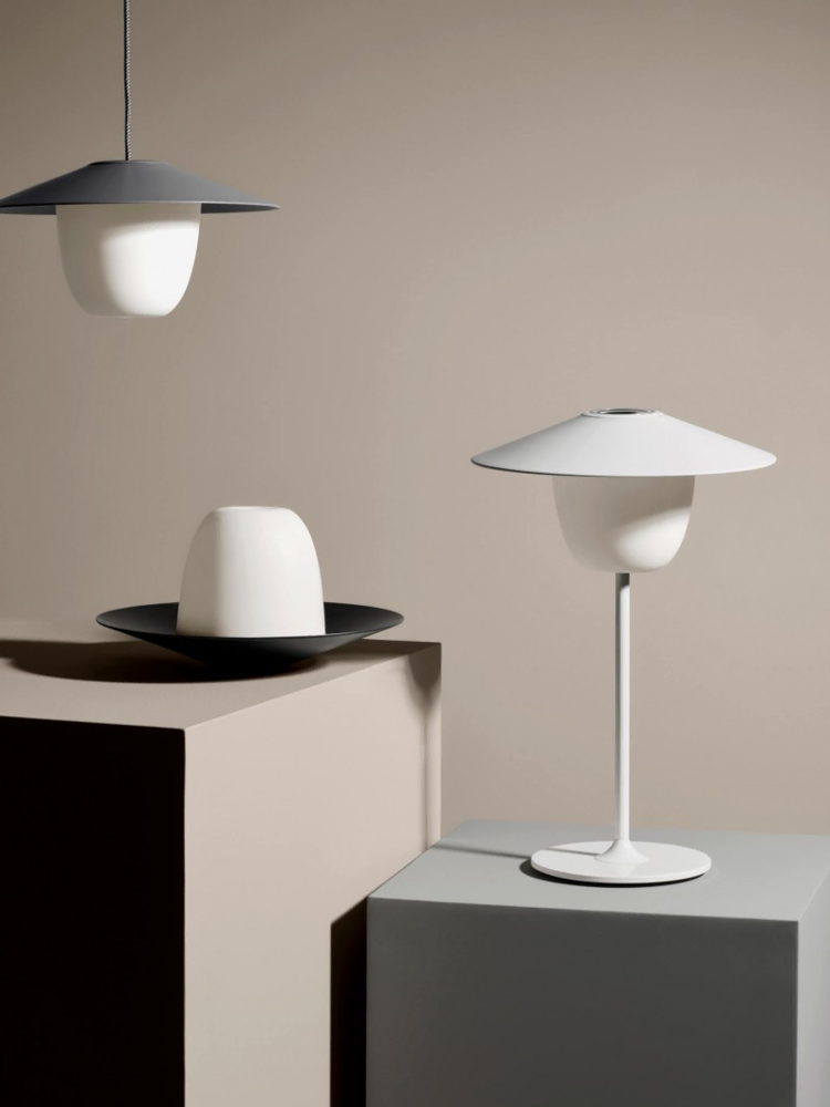 Bezprzewodowa lampa ogrodowa ANI LED, lampa wisząca oraz rozłożona podstawa lampy na postumentach ekspozycyjnych.