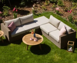 Modułowa sofa narożna Le Mans w kształcie litery L z jasnymi poduszkami i okrągłym drewnianym stolikiem kawowym na trawniku.