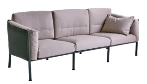 Sofa Delux: trzyosobowa sofa, jasne poduszki o fakturze bouclé, czarna rama ze stali nierdzewnej.